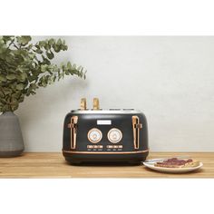 a black toaster sitting on top of a wooden table next to a plate of food