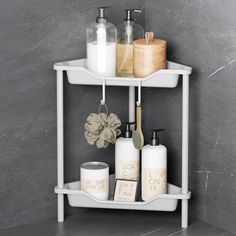 a bathroom shelf with soap, lotion and other items on it in front of a gray wall