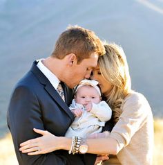 a man and woman holding a baby in their arms