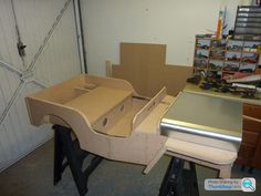 an unfinished car is being built in a garage with tools on the workbench