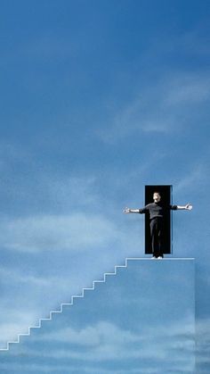 a man standing on top of a stairway with his arms outstretched in the air above him