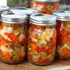 several jars filled with pickled vegetables sitting on top of a wooden table