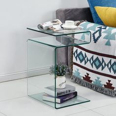 a glass table with some books on it and a couch in the backround