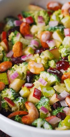 a salad with broccoli, red onions, and other vegetables in a white bowl