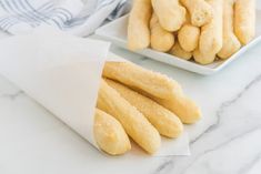 some food is on a white plate and next to another plate with breadsticks