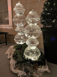 three clear glass balls on top of a christmas tree with lights in the middle and evergreens around them