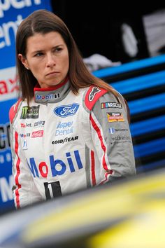 a woman standing in front of a blue car