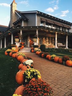 a house with pumpkins and flowers on the front lawn