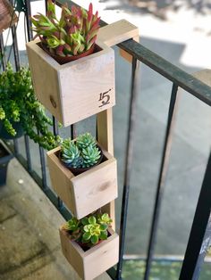 three wooden planters with succulents in them on a balcony railing next to potted plants