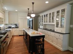 a large kitchen with white cabinets and black counter tops is pictured in this image, there are two stools at the center of the island