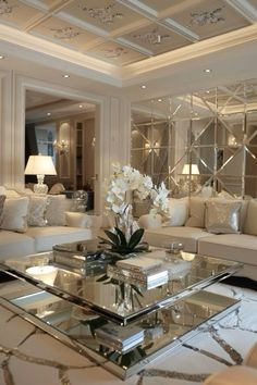 a living room filled with white furniture and lots of mirrors