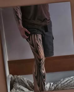 a man standing in front of a mirror with tattoos on his legs and leggings