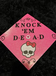 a pink graduation cap that says knock em dead with a skull and bow on it