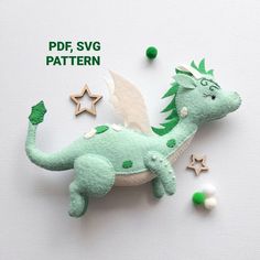 a green dragon brooch sitting on top of a white table next to stars and confetti