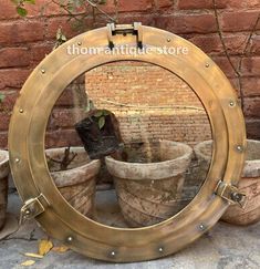 a mirror that is sitting on the ground near some potted plants in front of a brick wall