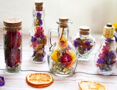 several glass bottles filled with dried flowers and orange slices sitting on a table next to each other