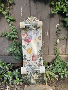 a skateboard is sitting on the ground in front of a wall with ivy growing around it