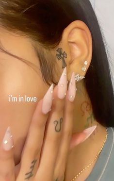 a woman with tattoos and piercings on her face is covering her ears while she has her hand under her ear