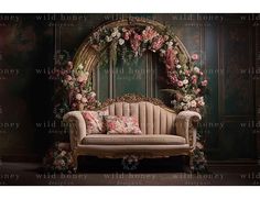 a couch sitting in front of a wall with flowers on it and a mirror behind it