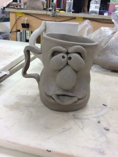 a clay face mug sitting on top of a table