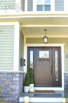 the front door of a house with two potted plants on the steps and an entryway