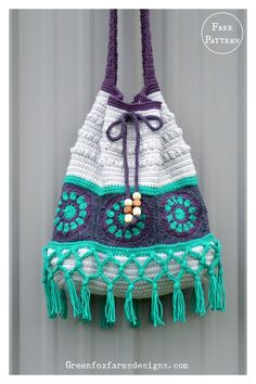 a crocheted purse hanging from a hook on a wall with tassels