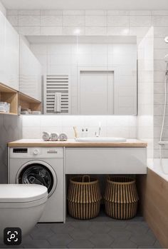 a washer and dryer in a bathroom with white tiles on the walls, wooden shelves above