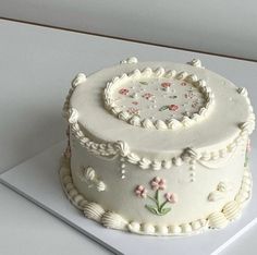 a white cake with flowers and seashells on it sitting on top of a table