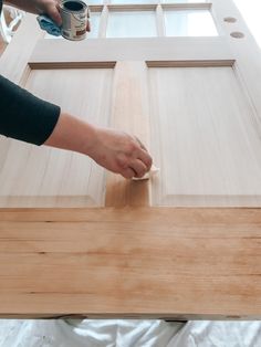 someone using a brush to paint the trim on a wooden door with wood grains