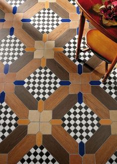 a wooden table sitting on top of a checkered tile floor next to a red chair