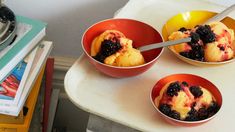 three bowls filled with ice cream and fruit on top of a table next to a book