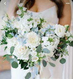 a bride holding a bouquet of white and blue flowers