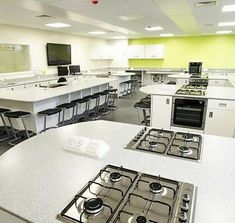 an empty kitchen with white counters and stove top ovens in front of the counter tops