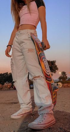 a girl in ripped jeans holding a skateboard