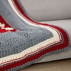 a crocheted blanket on a couch with a red and white afghan draped over it