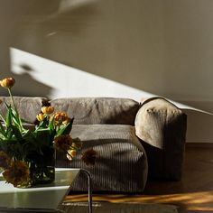 a vase with yellow flowers sitting on top of a table next to a couch in a living room