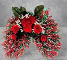 red roses and green leaves are arranged in a bouquet on top of a gray surface