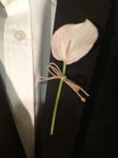 a white flower is tied to the lapel of a black suit