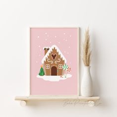 a pink christmas card with a gingerbread house in the snow and a white vase next to it