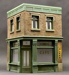 a small green building with windows and a sign that says cafe on the side of it