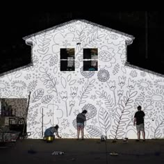 two men are painting the side of a building