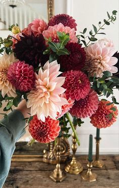 a person holding a bouquet of flowers in front of a mirror on a table with candles