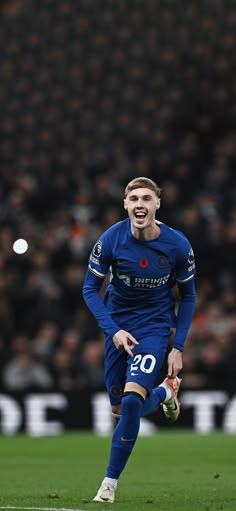 a soccer player running on the field with his mouth open and one foot in the air