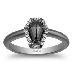 an engagement ring with a black diamond and white diamonds on the band, set in 18k white gold