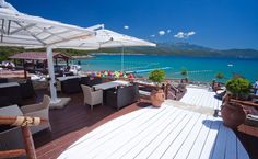 an outdoor dining area with umbrellas and chairs on the deck next to the ocean