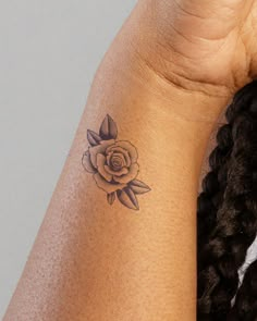 a woman's arm with a small rose tattoo on the left side of her arm