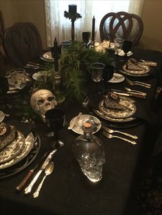 the table is set with silverware, plates and candles for halloween dinner guests to enjoy