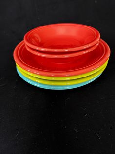 four red, yellow and blue plates stacked on top of each other in front of a black background