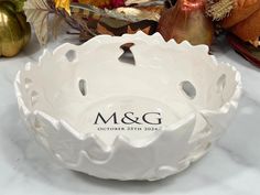 a white bowl sitting on top of a table next to fall leaves and pumpkins