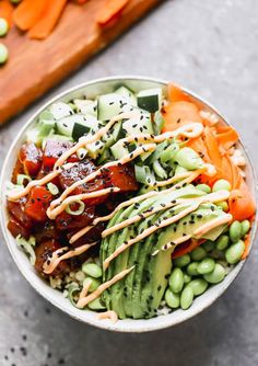 a bowl filled with vegetables and dressing on top of a table